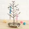 A jewelry tree stand with various necklaces and bracelets displayed on it, placed on a wooden surface with decorative balls in the background. Podgląd zdjęcia produktu
