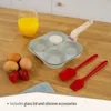 A frying pan with four circular sections, along with eggs, strawberries, a glass of orange juice, and silicone utensils, arranged on a wooden surface. Náhľad obrázku produktu