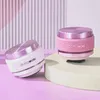 Two small, round, portable speakers are displayed on a light pink surface with a ribbed pink and white background. Podgląd zdjęcia produktu
