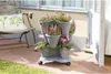 A multi-tiered planter with flowers on a patio next to a chair. Anteprima dell’immagine prodotto