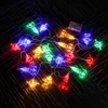 A string of colorful LED lights shaped like rockets, planets, and astronauts, powered by a battery pack, laid out on a dark, textured surface. Náhled obrázku produktu