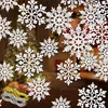 Hanging white snowflake ornaments with a blurred background of a Christmas tree and room. Produktbild-Vorschau