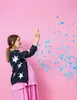 A pregnant woman is celebrating by throwing blue confetti. Produktbild-Vorschau