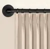 A close-up view of a black curtain rod with beige curtains hanging from it. Produktbild-Vorschau