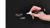 A hand holding a chalk marker writing on a blackboard. Anteprima dell’immagine prodotto
