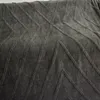A close-up view of a dark gray textured blanket with a geometric pattern. Produktbild-Vorschau