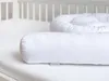 A white baby crib with a white crib bumper snake. Produktbild-Vorschau