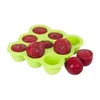 A green silicone mold filled with red baby food cubes, with a few cubes removed and placed next to it. Produktbild-Vorschau