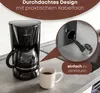 A black coffee maker with a glass carafe sits on a kitchen counter next to a mug of coffee. A close-up inset shows the power cord being plugged into the back of the coffee maker. Náhľad obrázku produktu