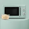 A retro-style microwave oven in mint green is shown on a light green pedestal, with a bowl of popcorn in front of it. Produktbild-Vorschau