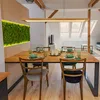 A dining room with a wooden table and chairs, set for a meal, with a moss wall feature. Náhled obrázku produktu