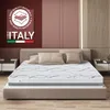 A mattress is displayed on a bed in a bedroom setting, with bedside tables and decorative wall panels in the background. A prominent "Made in Italy" badge with quality material claims is visible on the left. Voir les images du produit