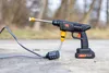 A cordless pressure washer with a battery pack and hose attachment sits on a concrete surface outdoors. Náhled obrázku produktu