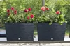 Two dark gray planters with red and pink flowers on a balcony or patio. Produktbild-Vorschau