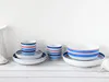 A set of striped ceramic dishes and mugs arranged on a white wooden surface against a white background. Náhľad obrázku produktu