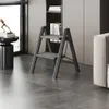 A modern living room with a black metal step stool placed on a gray tiled floor. Voir les images du produit
