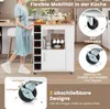 A woman is standing next to a white kitchen cart with a wooden top, which is filled with wine bottles and cups. The cart has wheels and is shown in a kitchen setting. Voir les images du produit