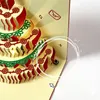 A close-up view of a pop-up birthday card shaped like a cake with decorative elements and lights. Podgląd zdjęcia produktu