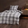 A bed with plaid bedding in a bedroom setting. Produktbild-Vorschau