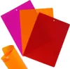 Three flexible cutting mats in pink, orange, and red are fanned out against a white background. A rolled-up orange mat is in the foreground. Voir les images du produit