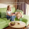 A young girl and a dog are relaxing on a green couch, with a mini projector on a coffee table. Náhled obrázku produktu