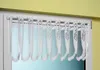 A close-up view of a white lace curtain with a rose pattern hanging on a curtain rod in a window. Produktbild-Vorschau