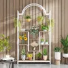 A multi-tiered plant stand filled with various potted plants, displayed against a wood-paneled wall. Anteprima dell’immagine prodotto