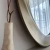 A close-up of a decorative vase with branches and a mirror in the background. Anteprima dell’immagine prodotto