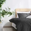 A bed with anthracite bedding and white pillows, next to a large potted plant. Produktbild-Vorschau