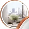 A round mirror with a copper frame and LED light, reflecting a city view and a potted plant. Produktbild-Vorschau