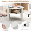 A white round coffee table with books and fruit on top, shown in a living room setting with pillows and a rug. Produktbild-Vorschau