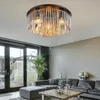 A modern living room with a sectional sofa, coffee table, and a large plant, featuring a ceiling light fixture. Produktbild-Vorschau