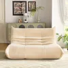 A beige sofa is placed in a living room setting, with a cabinet and artwork in the background. Produktbild-Vorschau