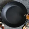 A top-down view of a black cast iron frying pan on a textured gray surface. Produktbild-Vorschau