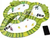 A dinosaur-themed race track toy set with miniature dinosaurs, trees, and a car. Produktbild-Vorschau