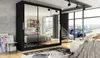A bedroom with a large black wardrobe with mirrored doors, a bed, and a view of a city from a large window. Produktbild-Vorschau