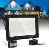 A floodlight with a motion sensor is shown in the foreground, with houses illuminated by floodlights in the background. Produktbild-Vorschau