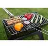 A portable grill with food items on it, set up on a grassy area. Podgląd zdjęcia produktu