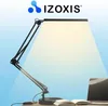 A desk setup with a lamp, laptop, and book, illuminated by the lamp. Náhľad obrázku produktu