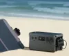 A portable power station and solar panel are set up on a sandy beach with the ocean in the background. Náhled obrázku produktu