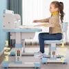 A young girl sits at a height-adjustable desk and chair set, drawing. Produktbild-Vorschau