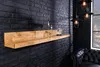 A wooden shelf mounted on a black brick wall, with decorative items and lighting fixtures. Produktbild-Vorschau