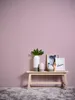 A minimalist arrangement of decorative objects on a wooden bench against a solid purple wall and a fluffy gray rug. Produktbild-Vorschau