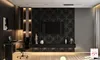 A modern living room or office space featuring a wall-mounted TV on a textured black panel, a desk with a laptop, and decorative elements. Produktbild-Vorschau