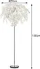 A floor lamp with a white, leaf-like shade and a chrome stand, shown with dimensions indicated. Produktbild-Vorschau