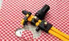 A rotary cutter and a small fabric circle are placed on a red and white checkered fabric. Náhled obrázku produktu