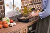 A person is cooking in a kitchen, with a backsplash featuring orchids. Náhľad obrázku produktu