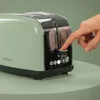 A hand is pressing a button on a green toaster. Anteprima dell’immagine prodotto