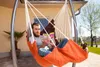 A man is reading a book while relaxing in an orange hammock chair outdoors. Produktbild-Vorschau