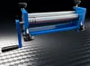 A blue metal rolling machine with silver rollers and a black handle is shown against a dark, textured background. Náhled obrázku produktu